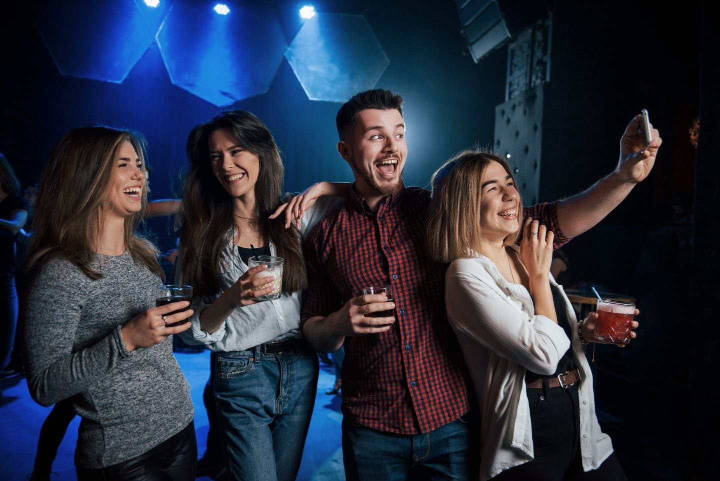 Joking around. Friends taking selfie in beautiful nightclub. With drinks in the hands