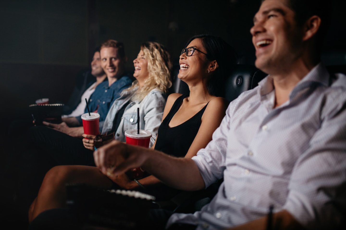 Young people in theater watching movie and smiling