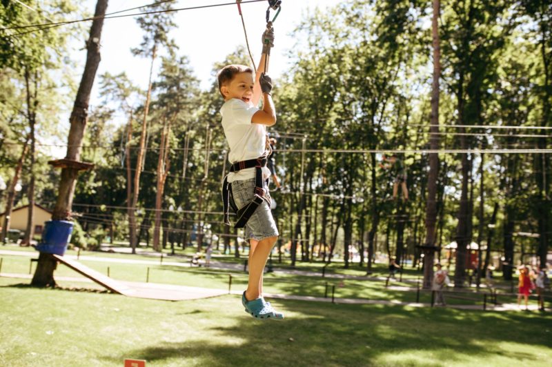 Little brave boy on zipline in rope park
