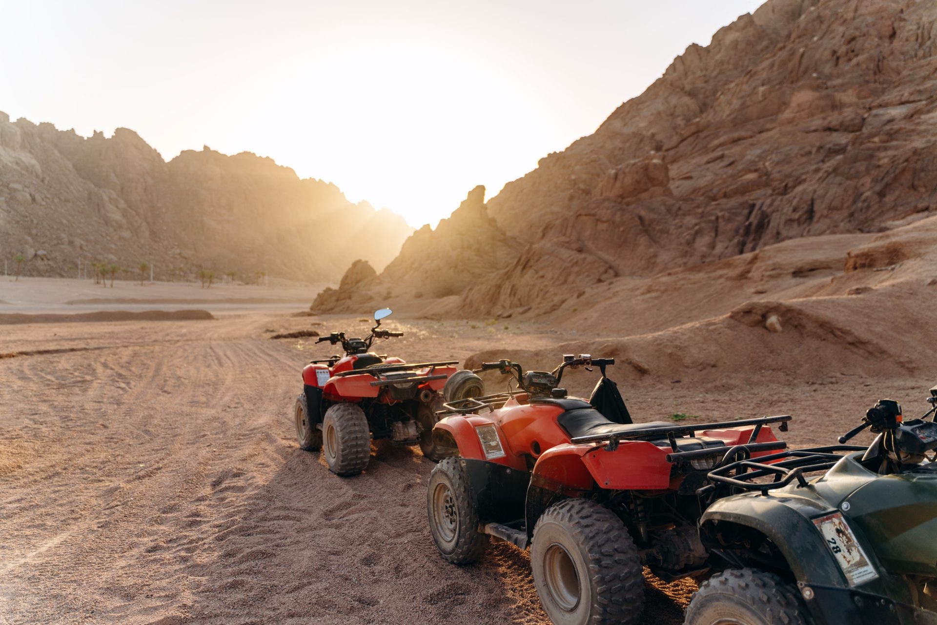 Column of ATVs in the desert at sunset. Sunny desert