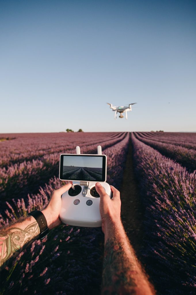 Man control drone with remote in flower field