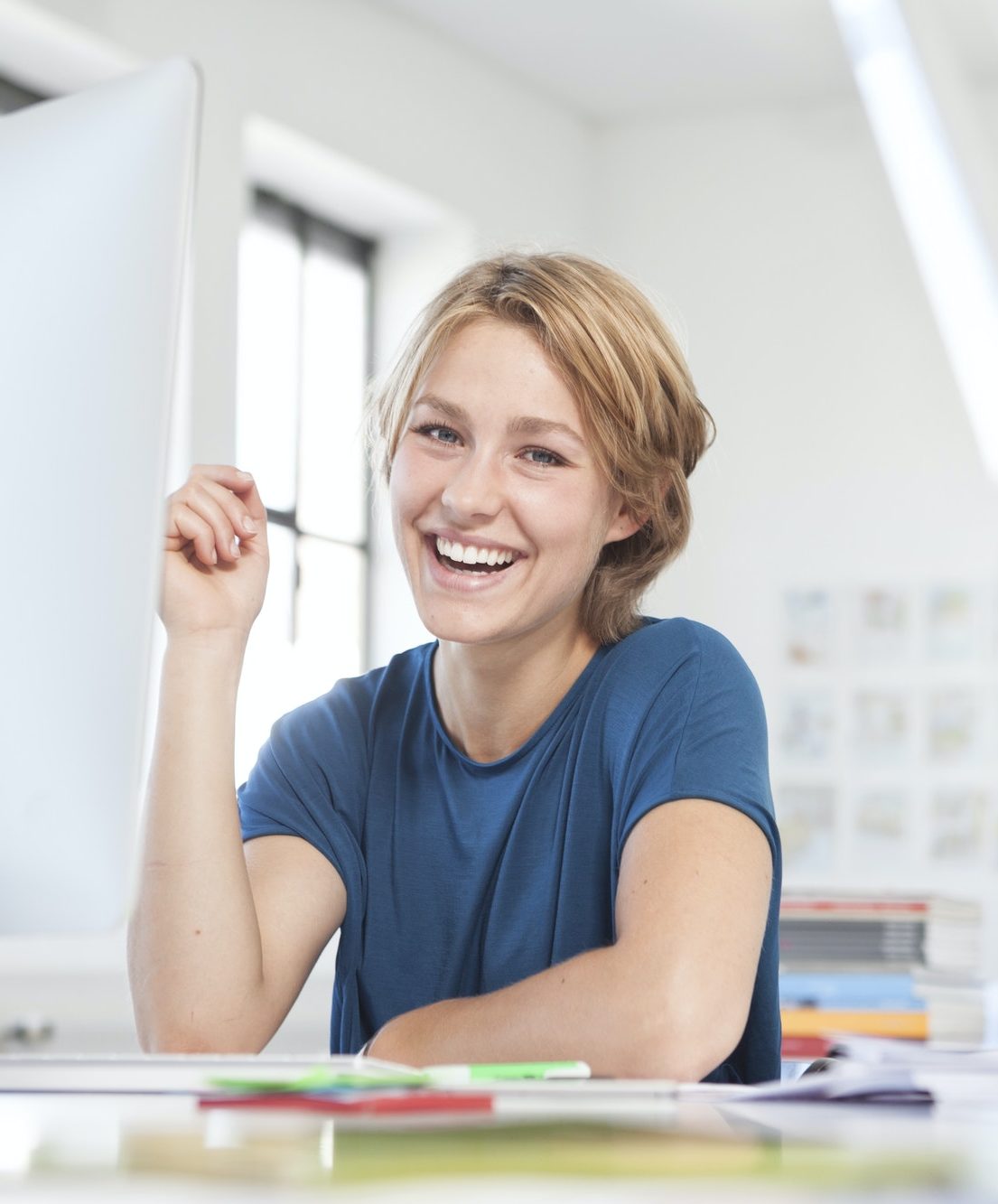 Portrait of happy young woman at her desk in a creative office