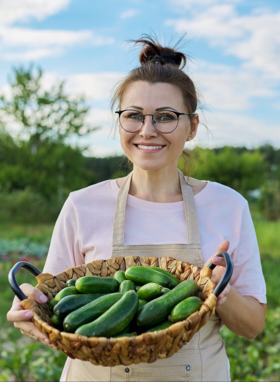 Portrait of woman farmer with basket of freshly picked cucumbers