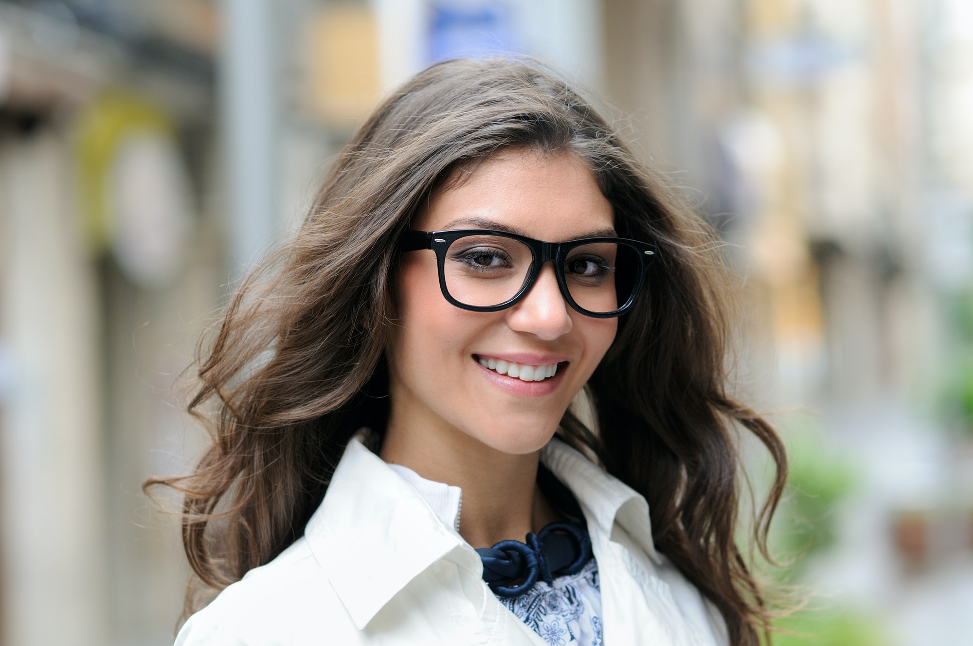 Beautiful woman with eye glasses smiling in urban background