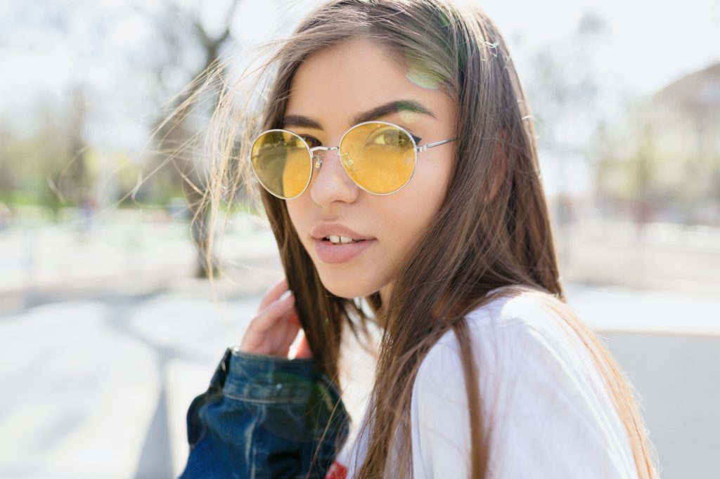 Close-up portrait woman with long light-brown hair and big eyes wears yellow spectator