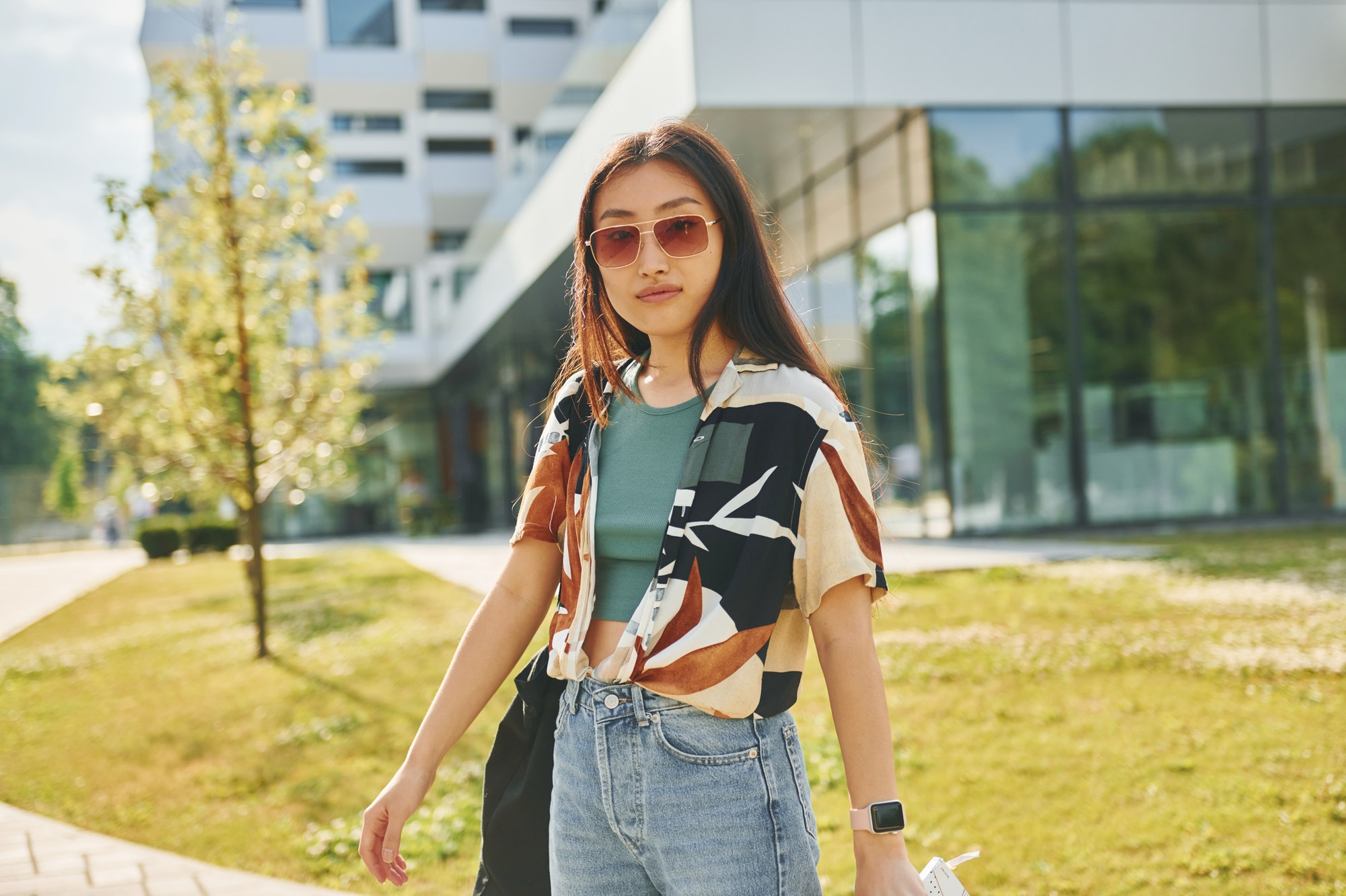 In sunglasses. Young asian woman is outdoors at daytime