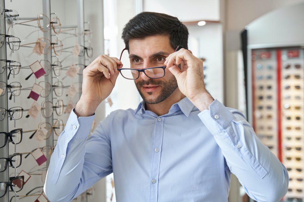 Male fitting glasses on his eye in optics store