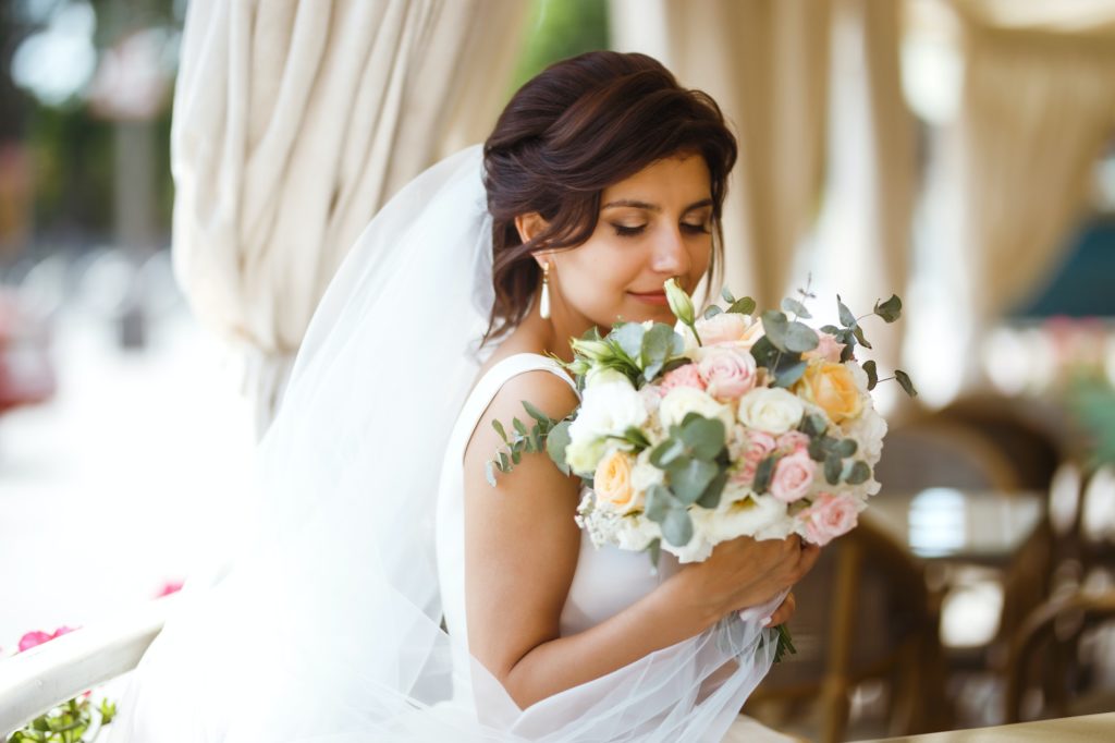 Beautiful bride with wedding flowers bouquet attractive woman in wedding dress. Happy newlywed woman