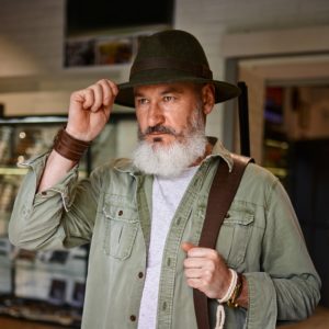 Bearded male hunter tries on hat in gun store