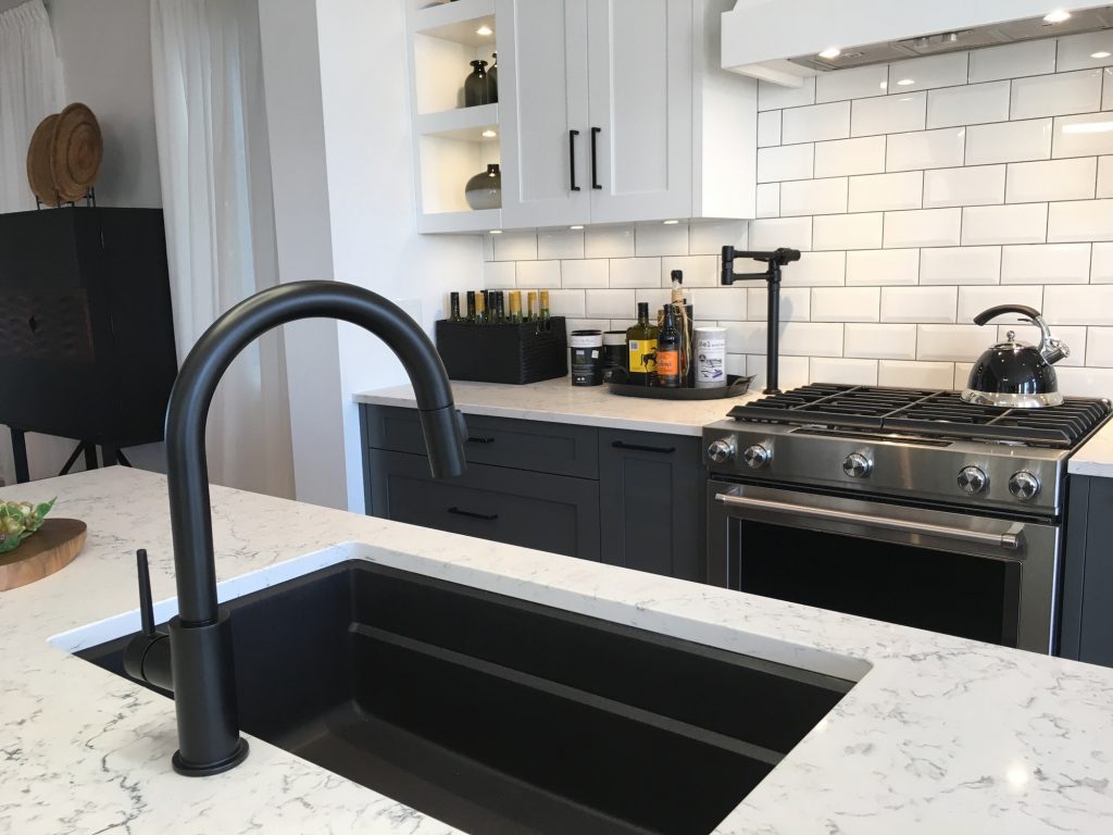 Modern kitchen design, undermount black sink and black faucet add dramatic contrast to white counter