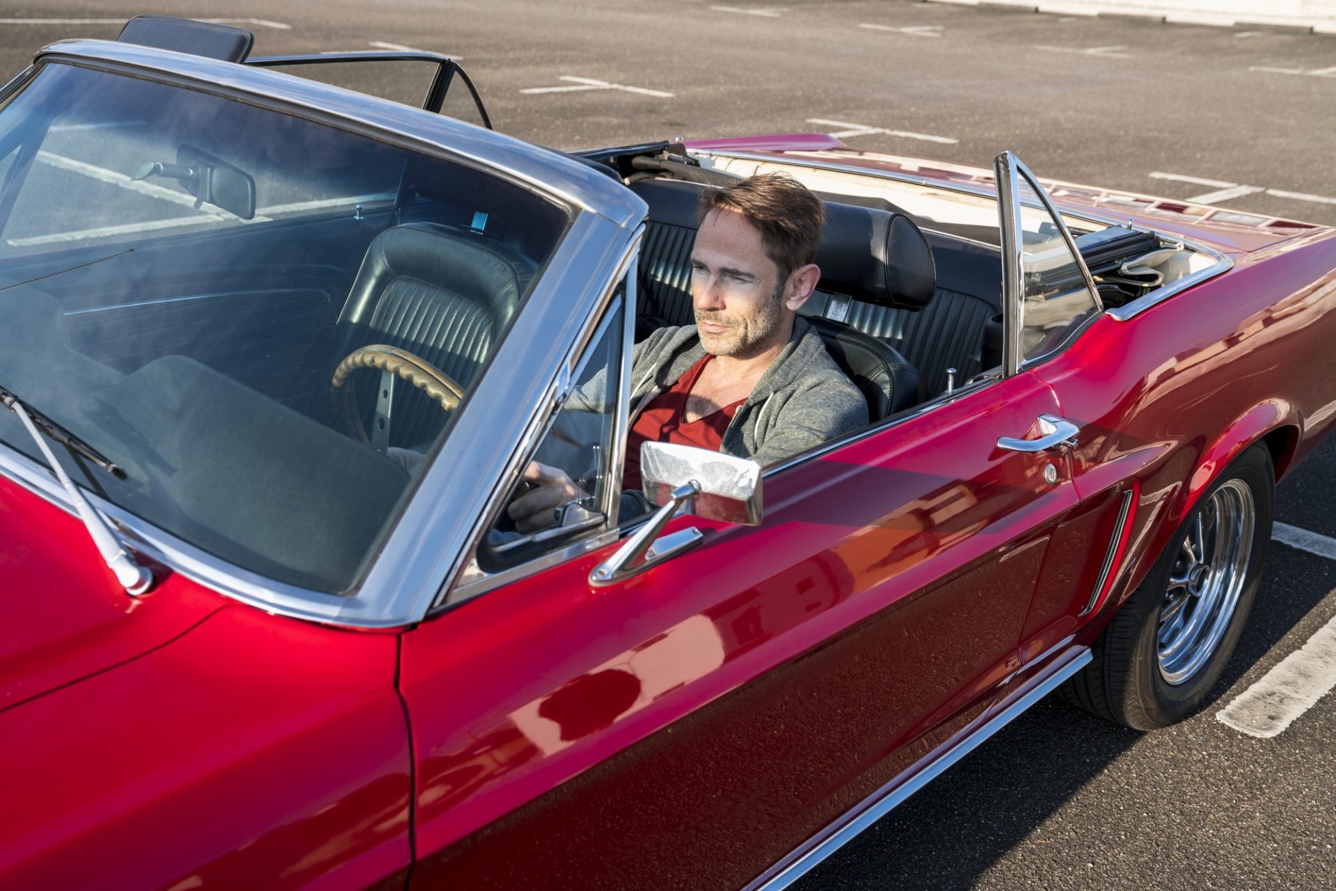 Mature man sitting in his red sports car