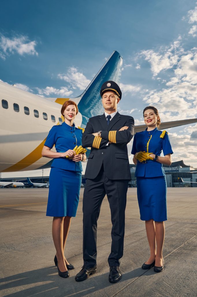 Male pilot and air hostesses posing for the camera outdoors