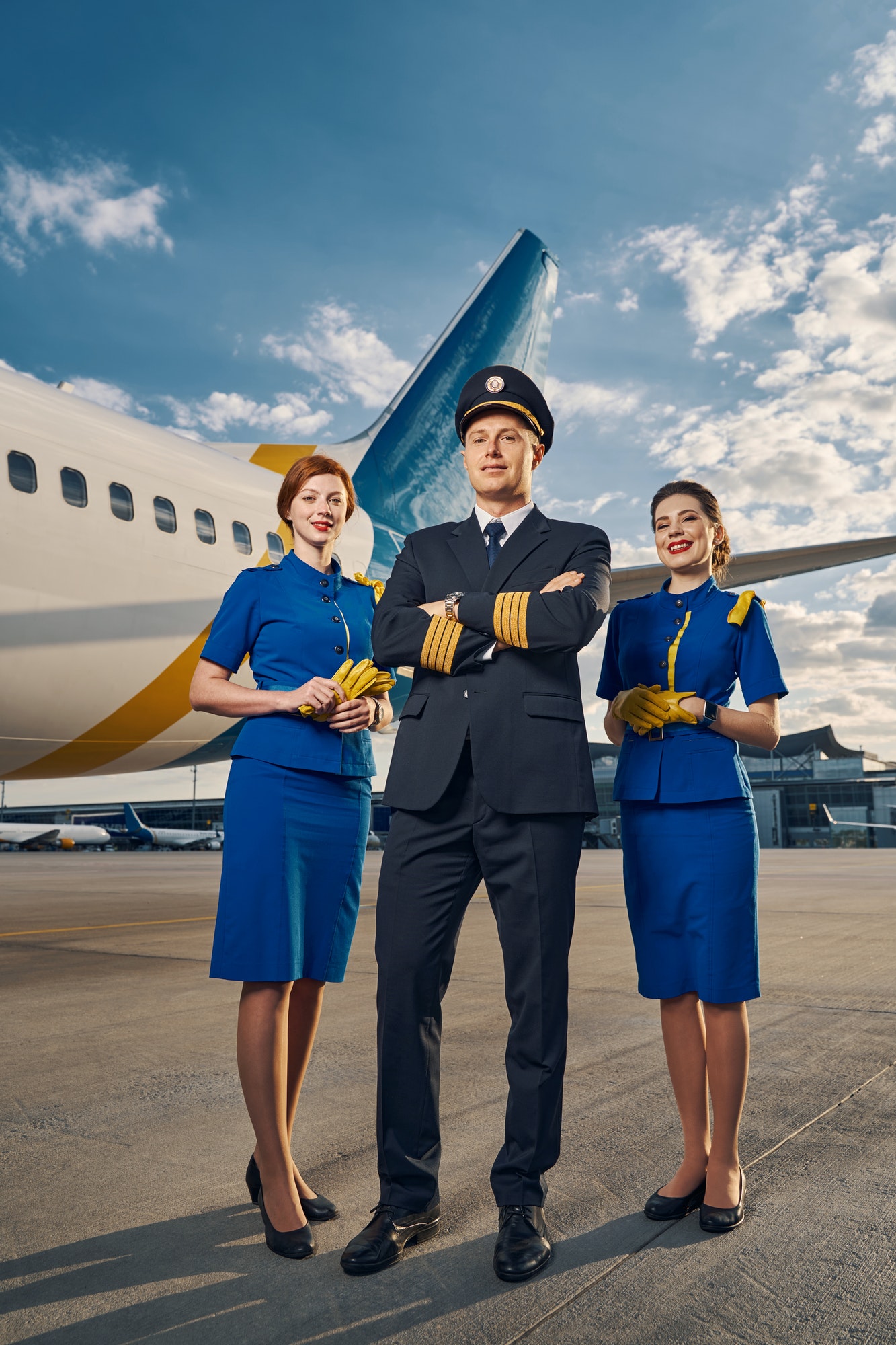 Male pilot and air hostesses posing for the camera outdoors