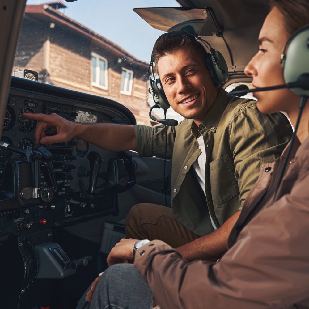 Cheerful young man giving flight lesson to woman