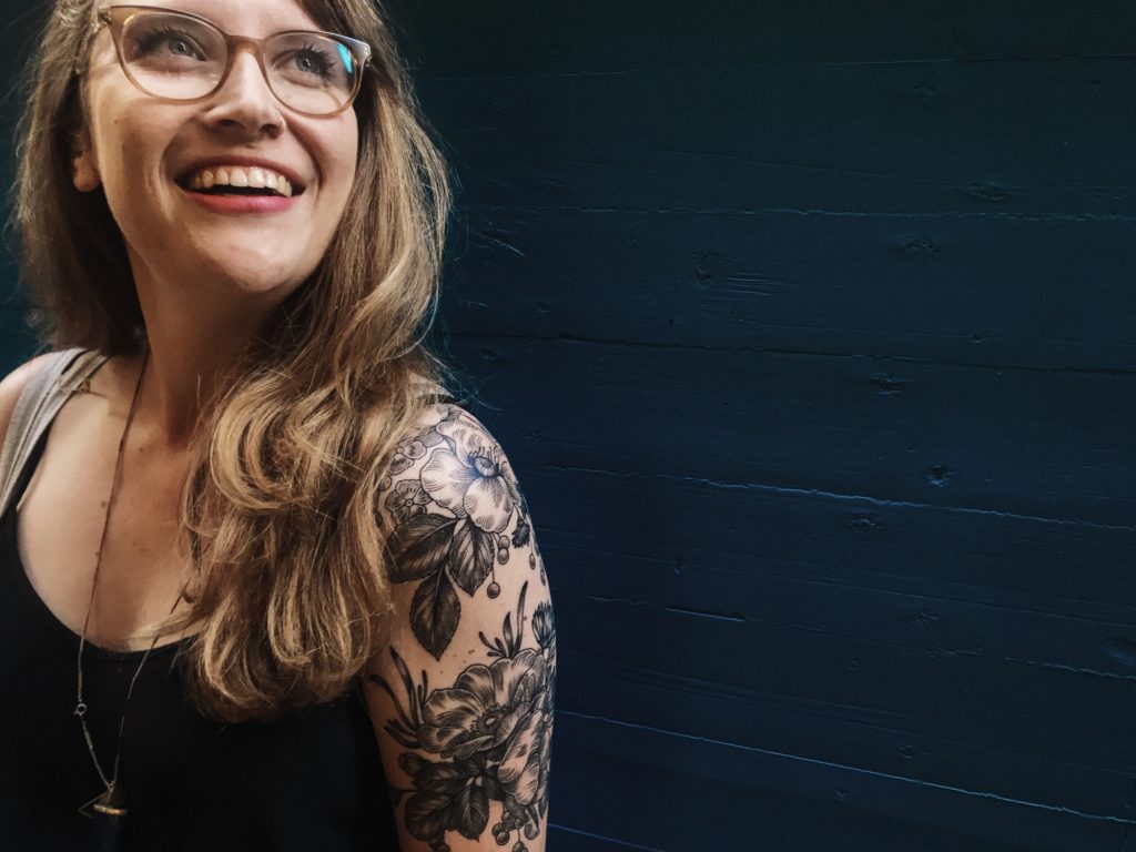 Woman with tattoos & glasses.