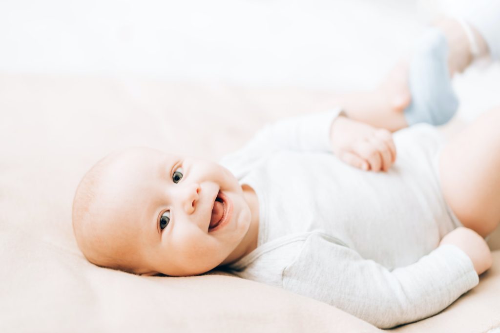 Newborn laughing baby lying on the bed. Caring for newborn children