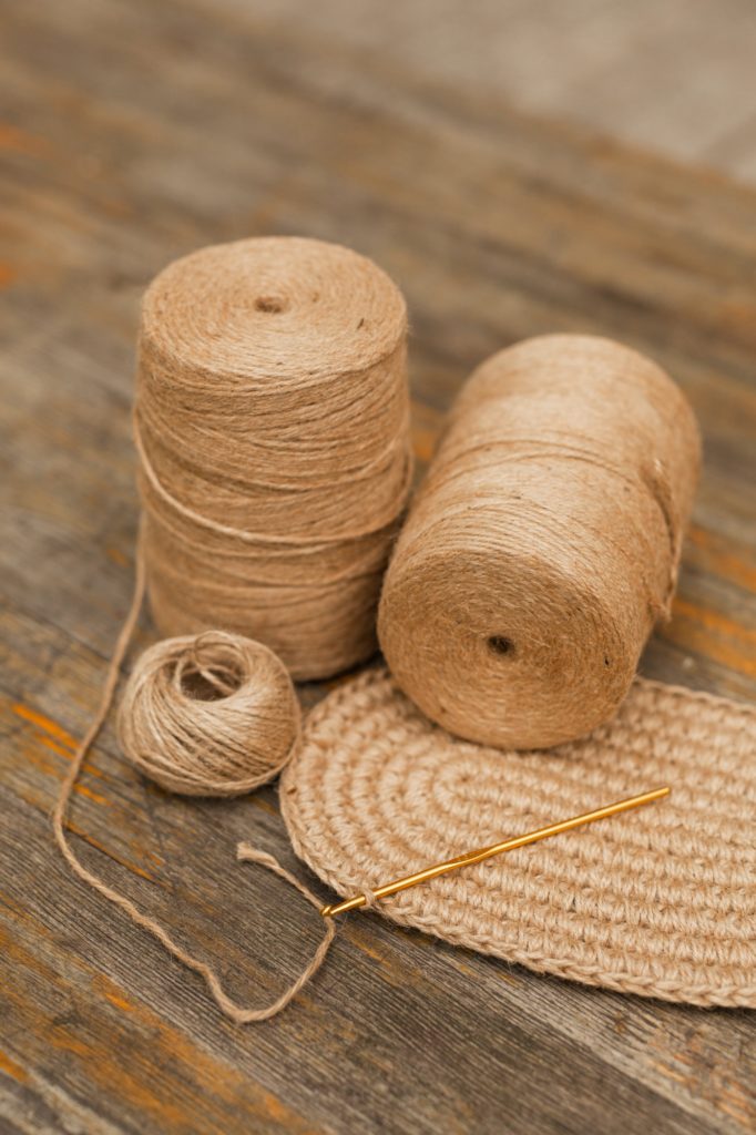 Bobbins of natural jute thread for knitting, handicraft on a wooden background