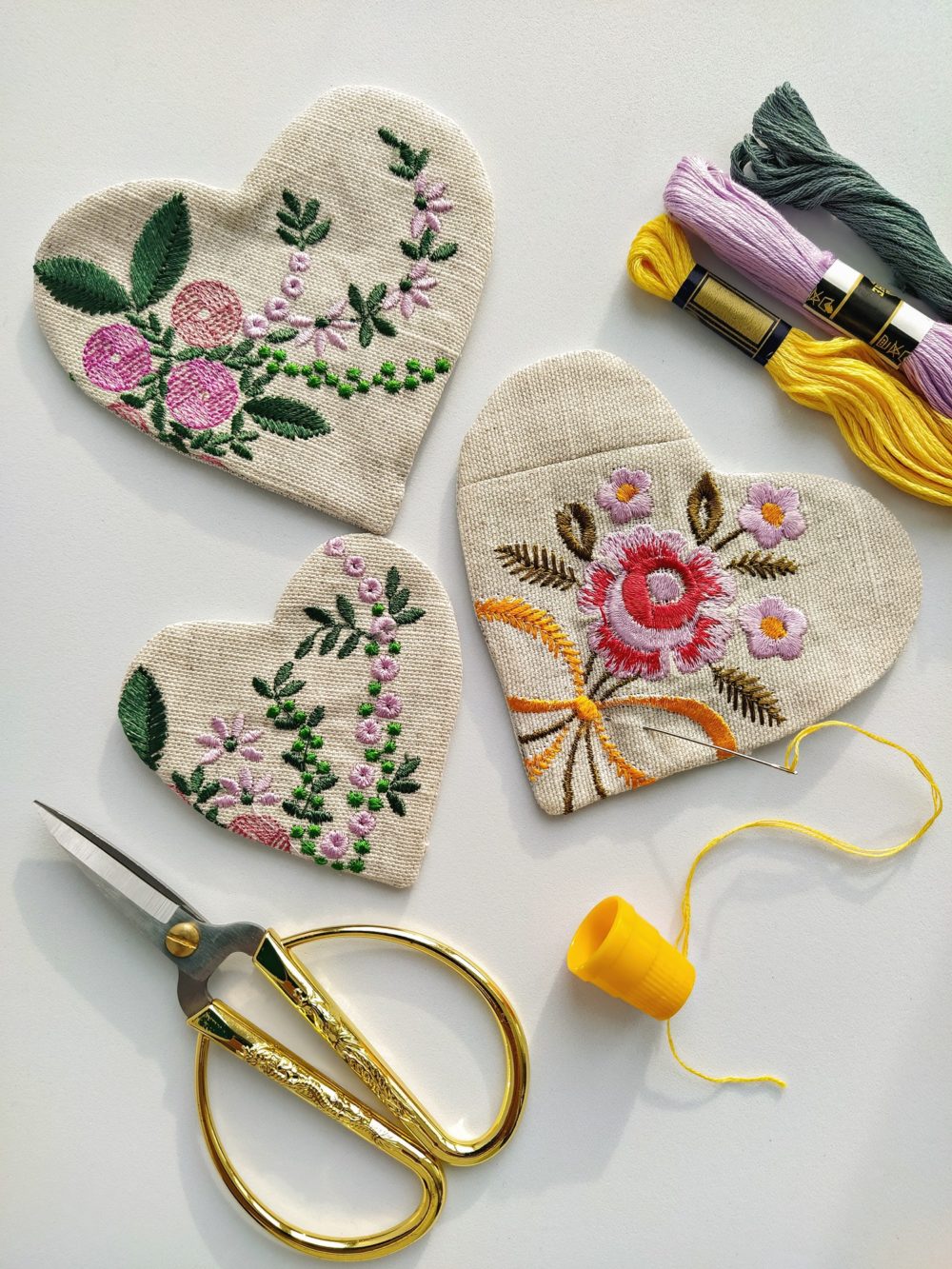 Fabric linen hearts with floral embroidery and vintage scissors, needle, thread on white