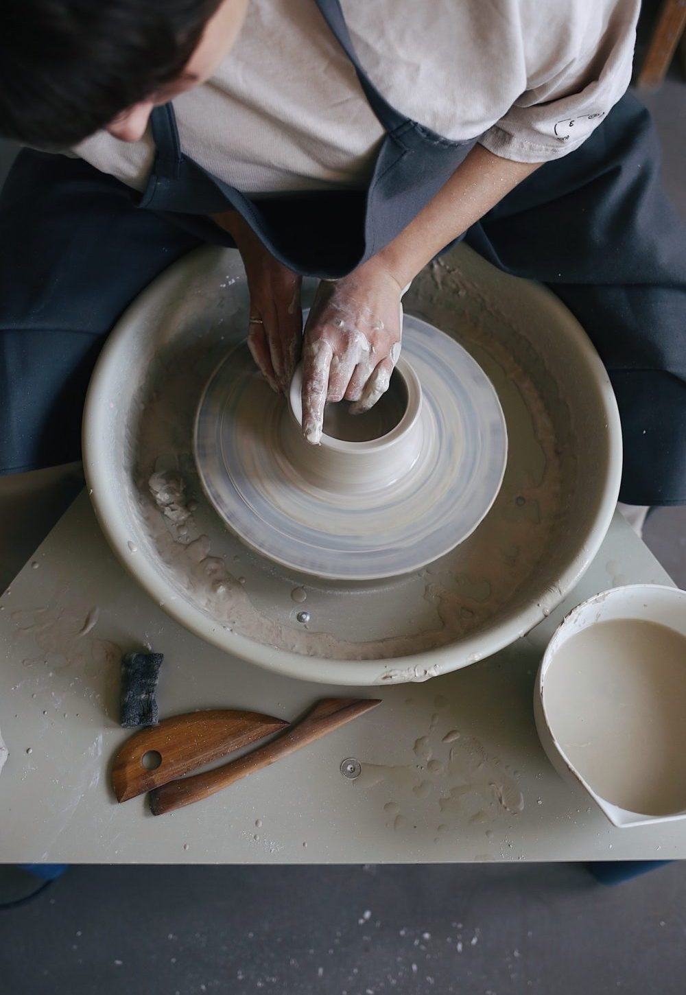 Working on a potter's wheel with a clay in a pottery studio. Clay jug