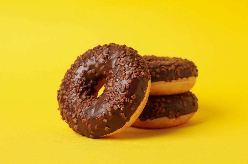Tasty donuts on yellow background, close up