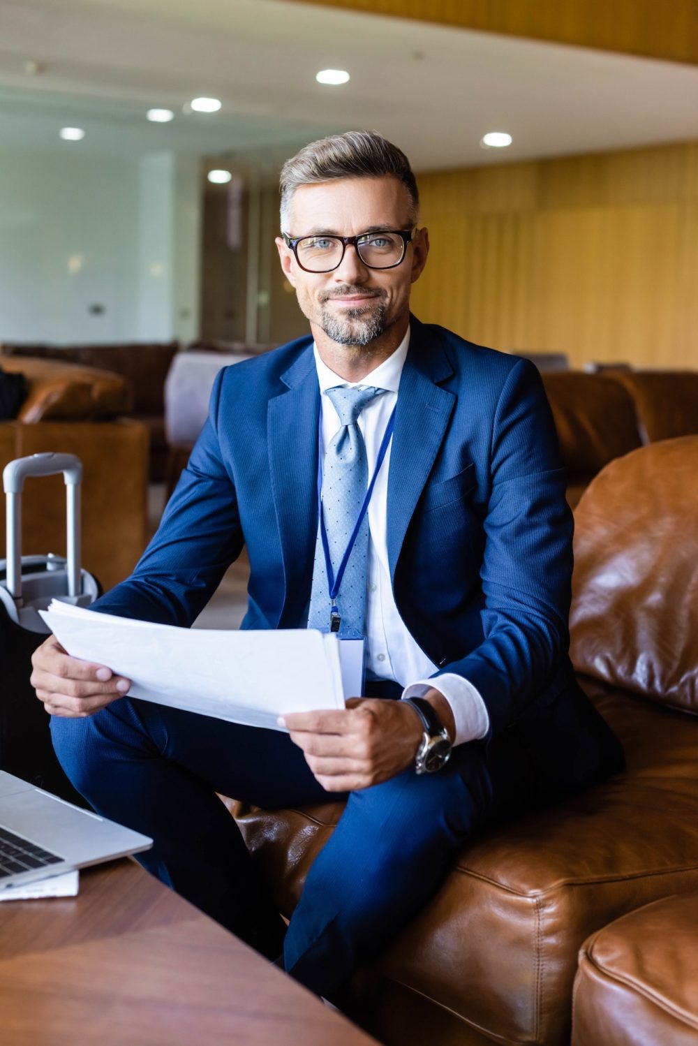 handsome businessman in formal wear and glasses holding documents