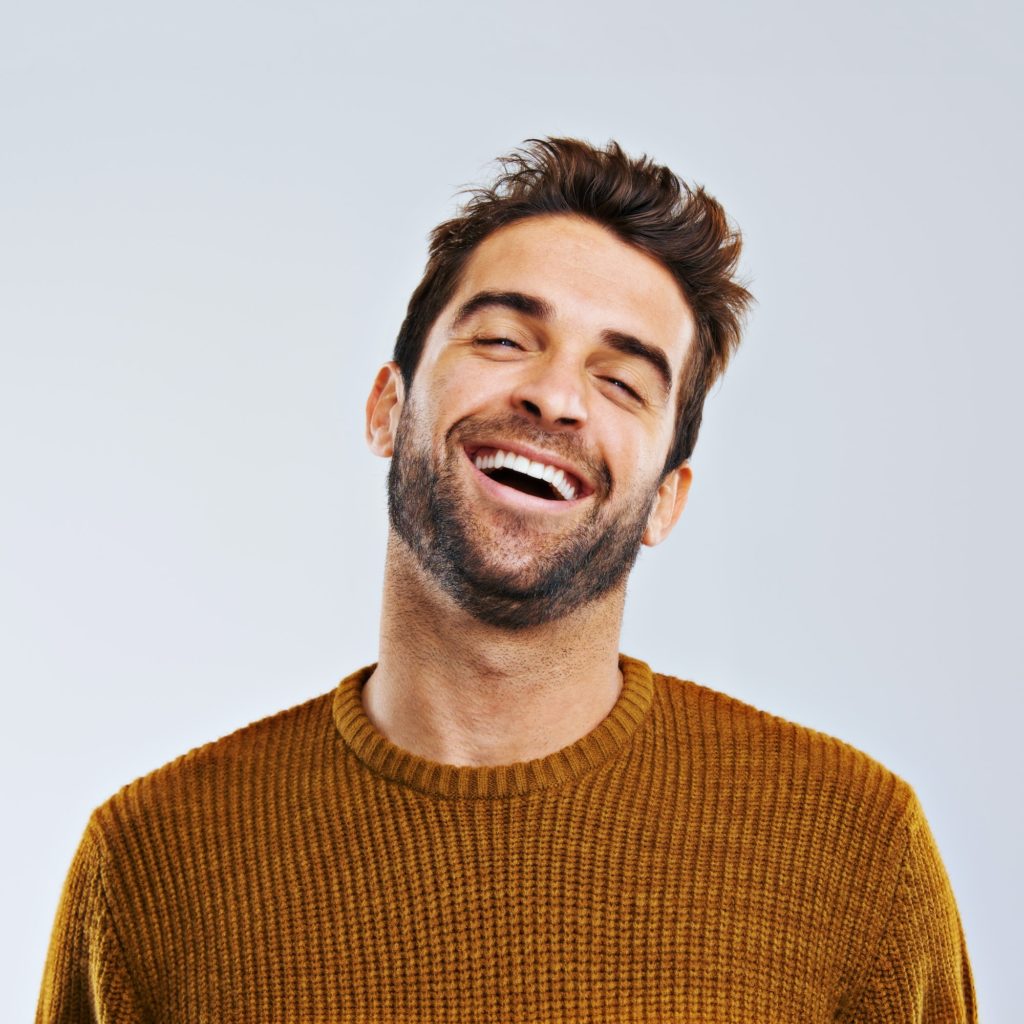Studio shot of a happy and handsome man laughing against a gray background