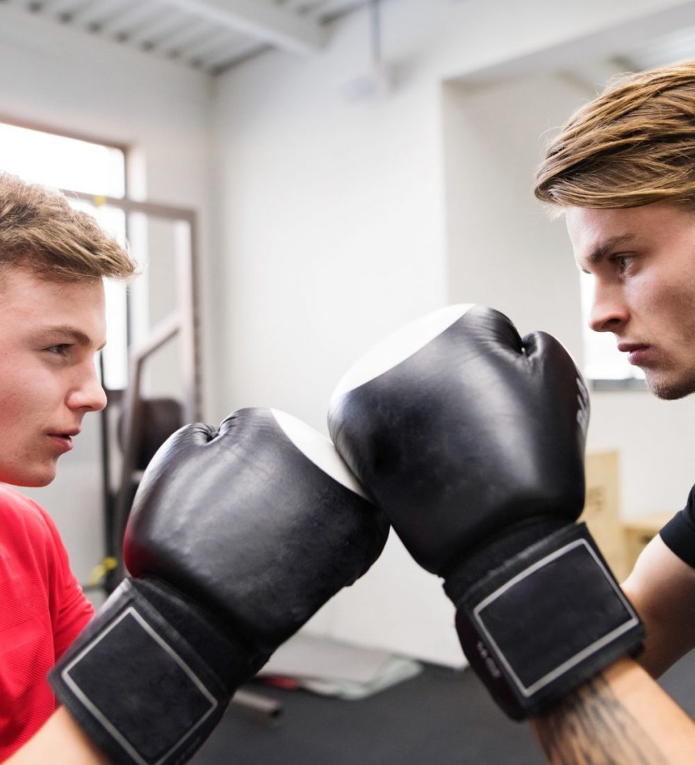 Two fit handsome men in gym boxing.