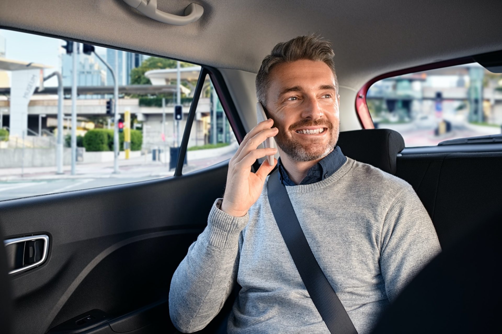 Happy mature man in taxi talking on phone