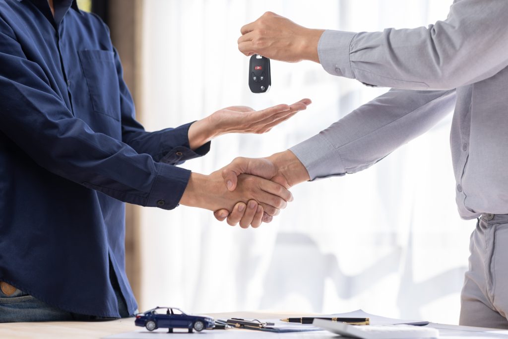 Car rental service sales give the car key concept. Close up view Hand of agent handshake to the cust