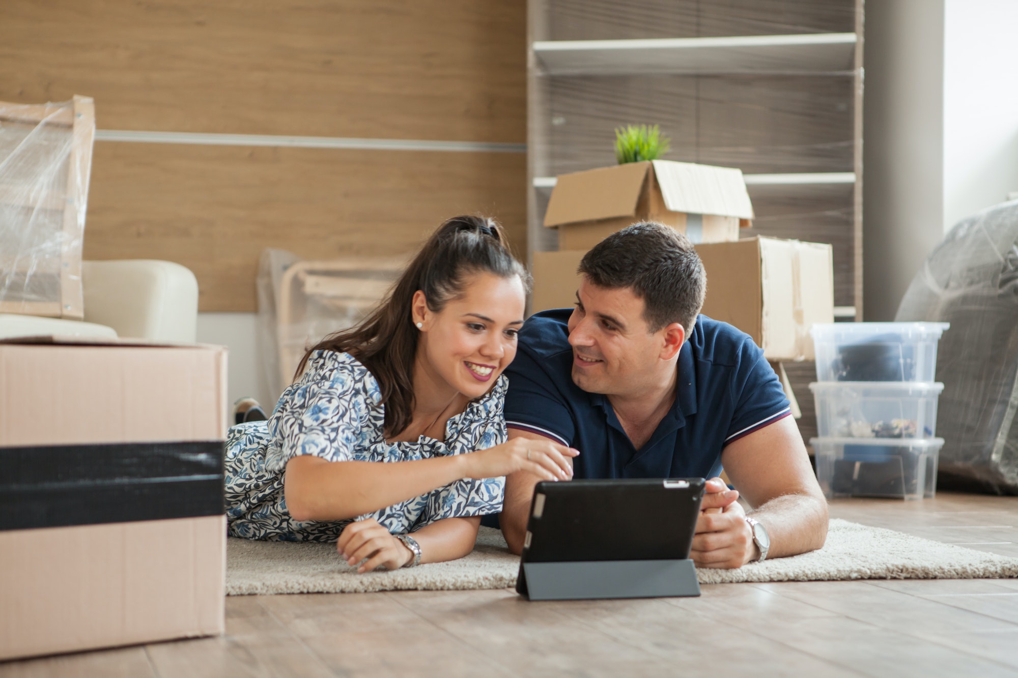 Couple planning decoration on line with a tablet and moving home in the living room