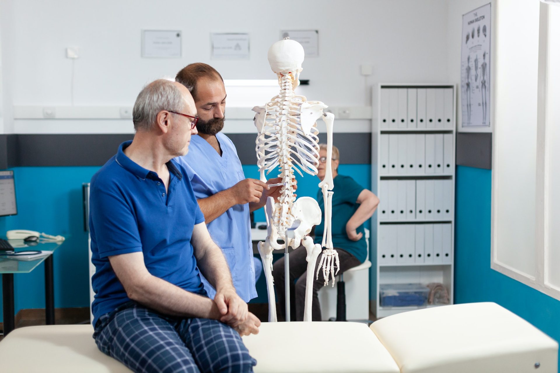 Orthopedist explaining spinal cord on human skeleton