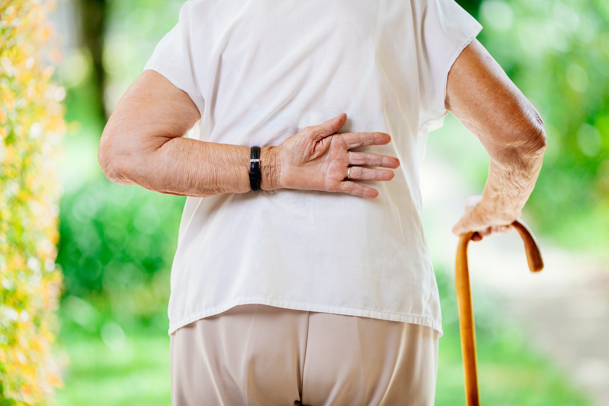 Elderly woman outdoors with back pain