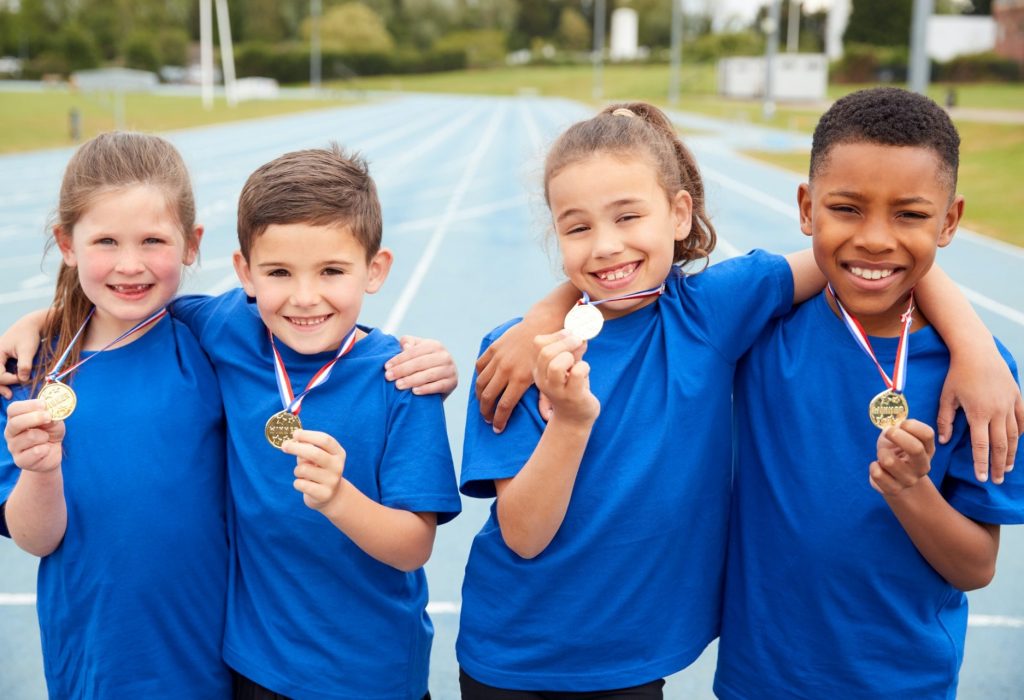 Portrait Of Children Showing Off Winners Medals On Sports Day