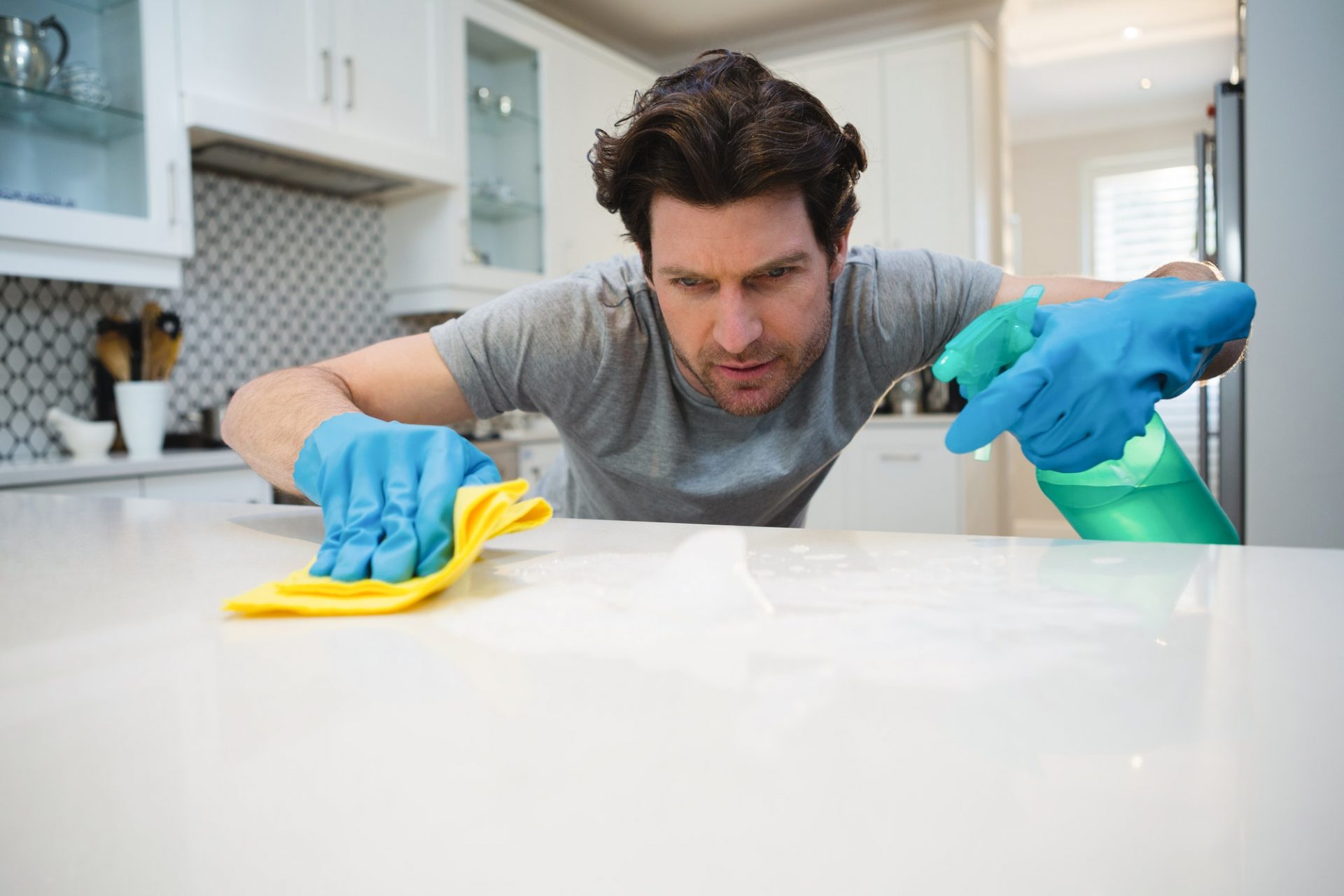 Man cleaning kitchen worktop at home
