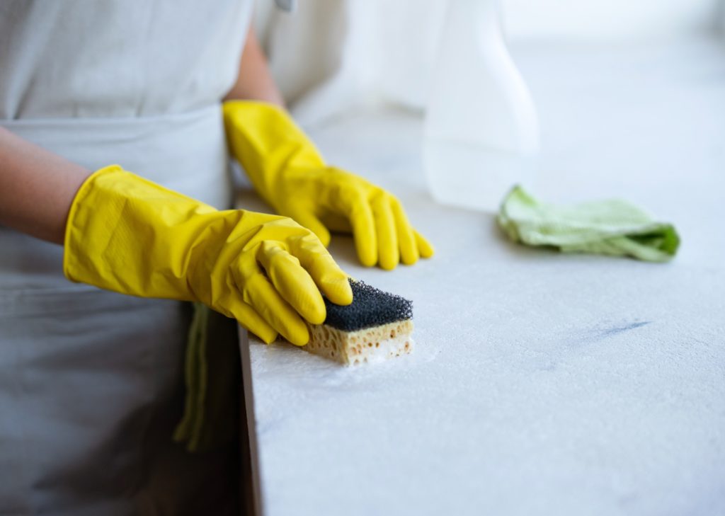 cleaning service. A woman in a gray apron and yellow rubber gloves. Professional housekeeping