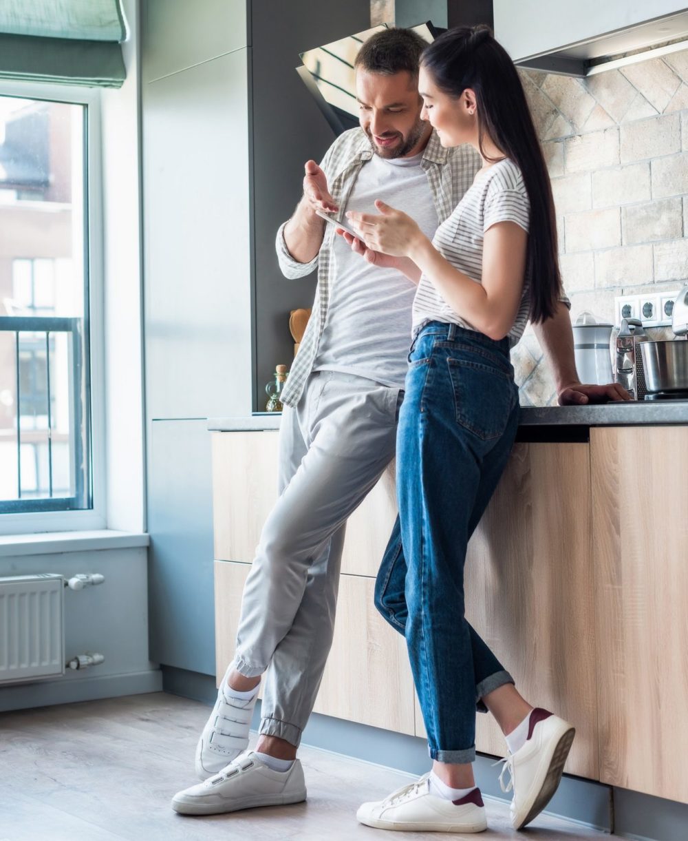 couple using smartphone together in kitchen, smart home concept