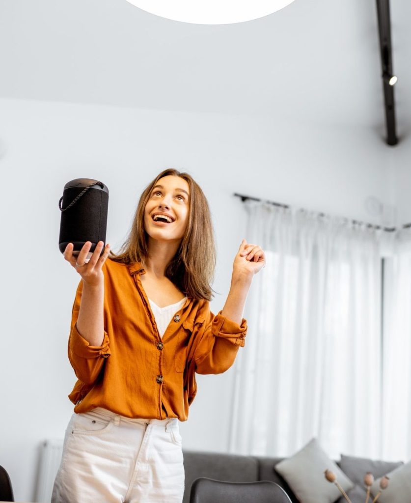 Woman controlling light with a smart speaker at home