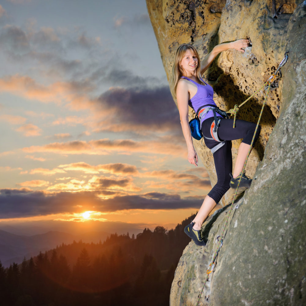 Female climber climbing with rope on a rocky wall