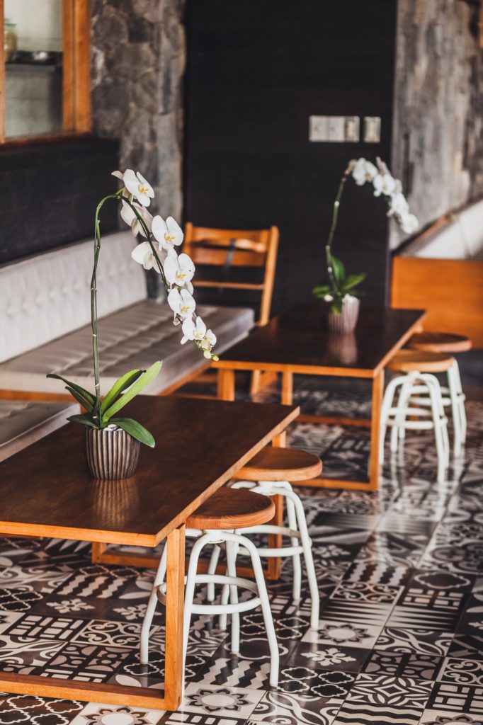 Modern wooden furniture in cafe on floor with black and white ornament tile. Two chairs, table