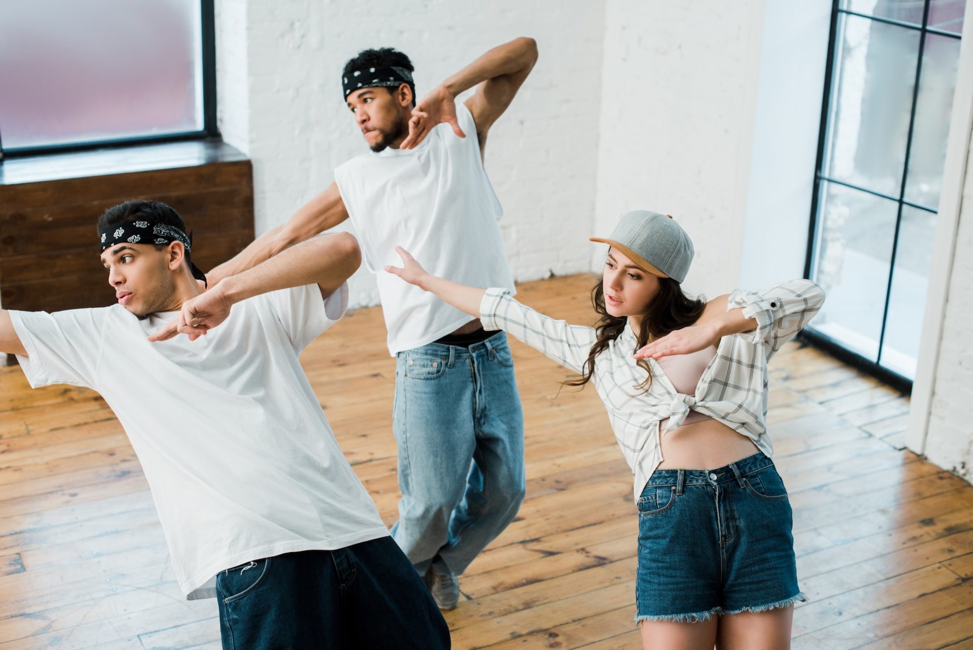 multicultural dancers gesturing while dancing hip-hop in dance studio