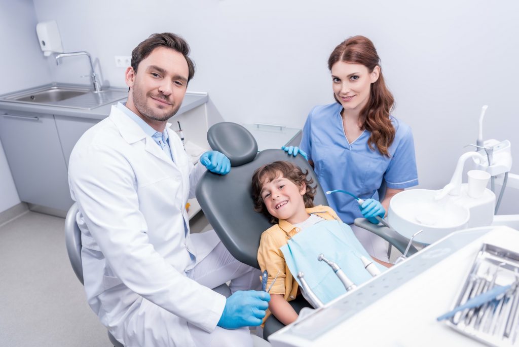 dentists preparing little boy for examining teeth at dentist office