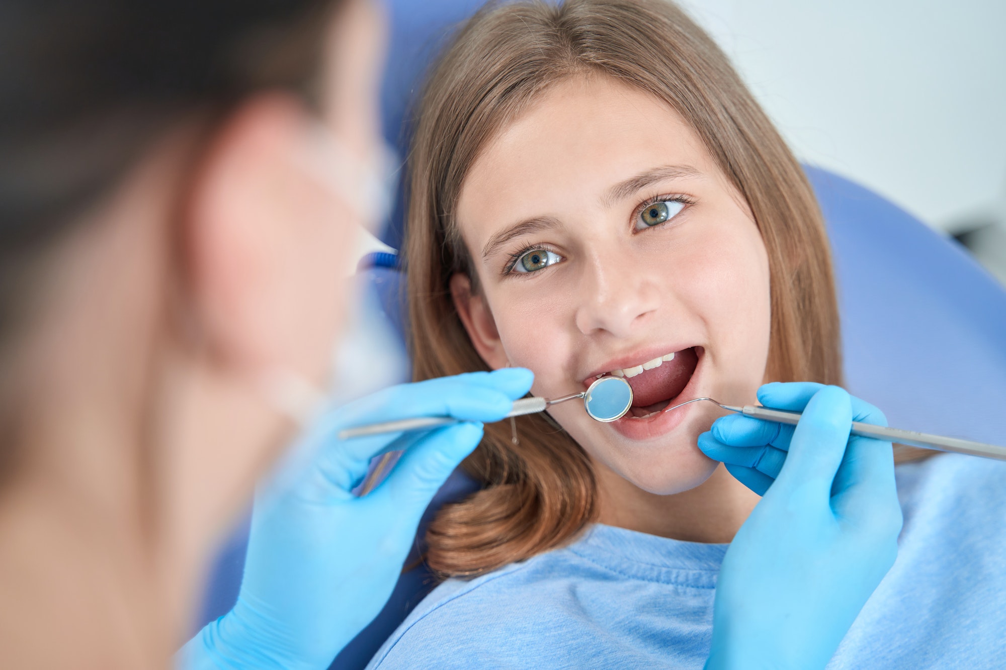 Professional stomatologist inspecting oral cavity of teenager