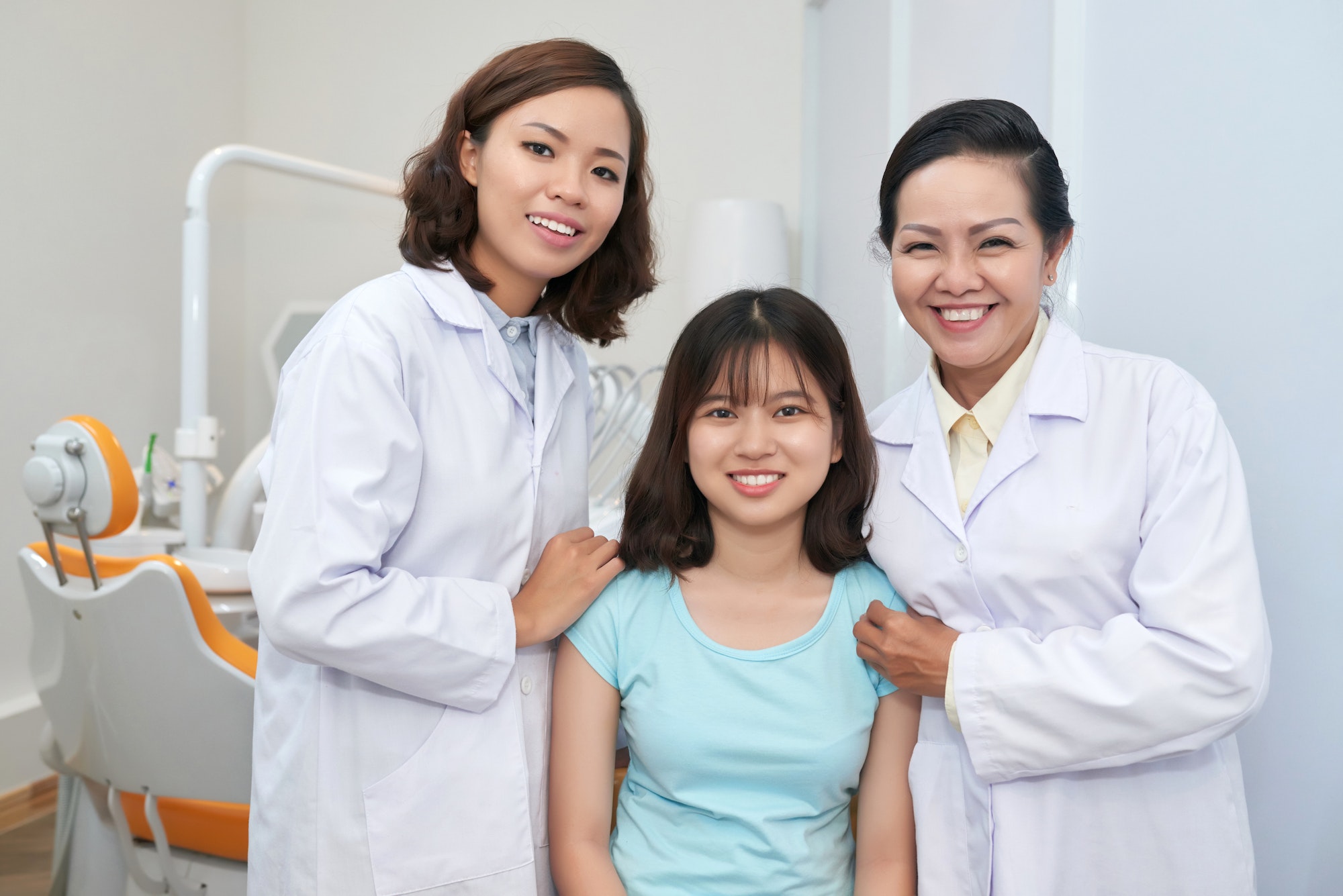 Smiling doctors with girl in dental office