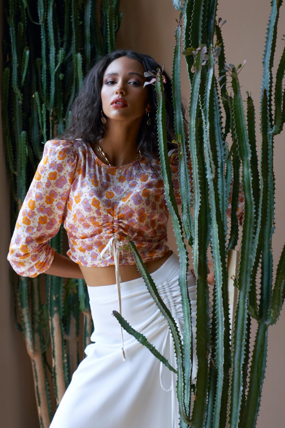 Gorgeous fashionable mulatto female model among cactuses