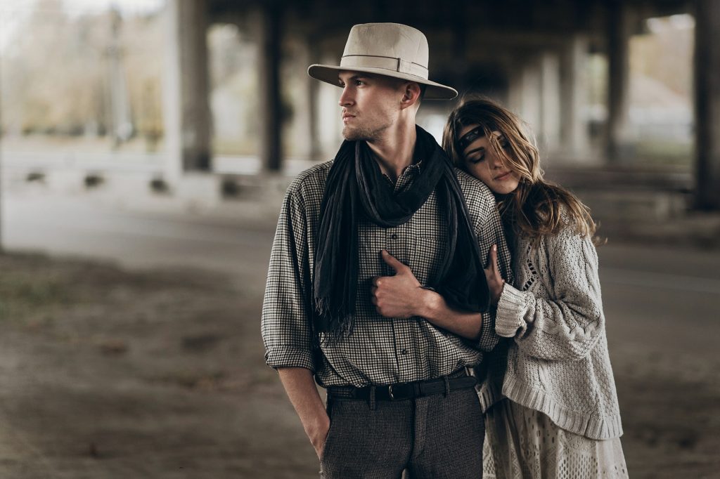 Handsome cowboy man with hat being hugged by beautiful indie woman
