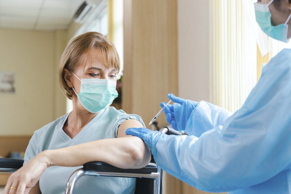 elderly woman patient getting covid-19 or coronavirus vaccine in a wheelchair ​at the hospital.