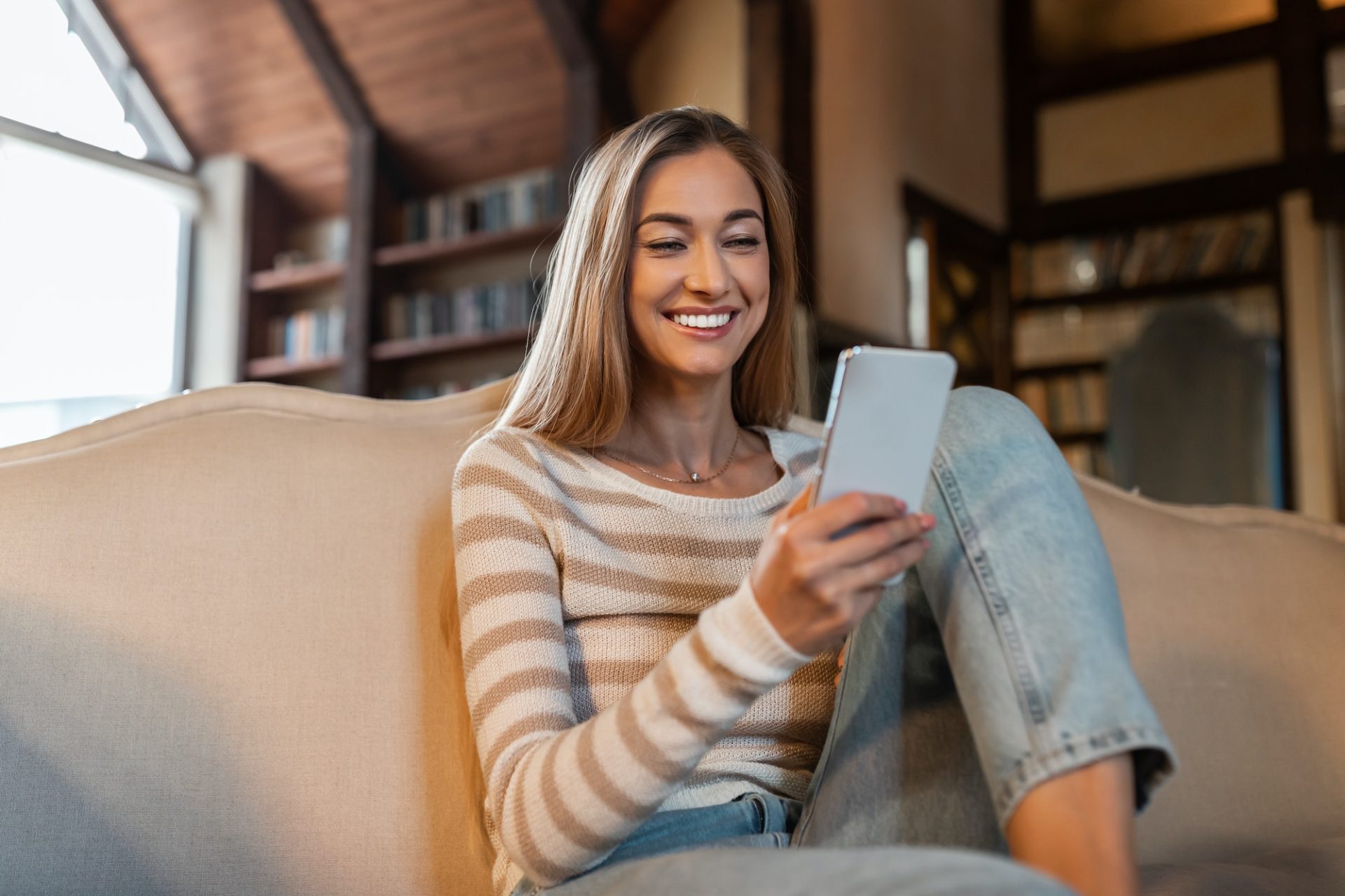 Portrait of smiling woman using smartphone at home