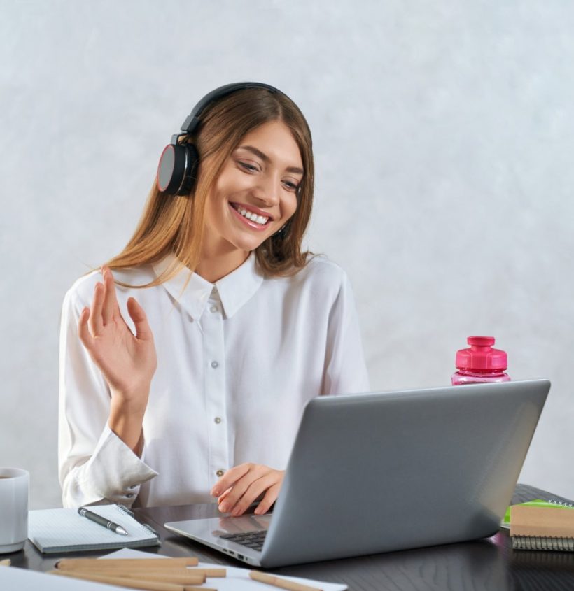 Woman waving and talking during online education on laptop