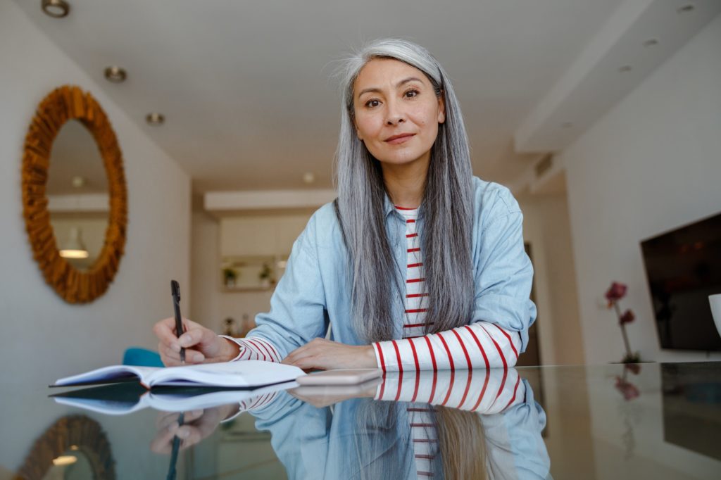 Woman sitting at the table and taking notes at home