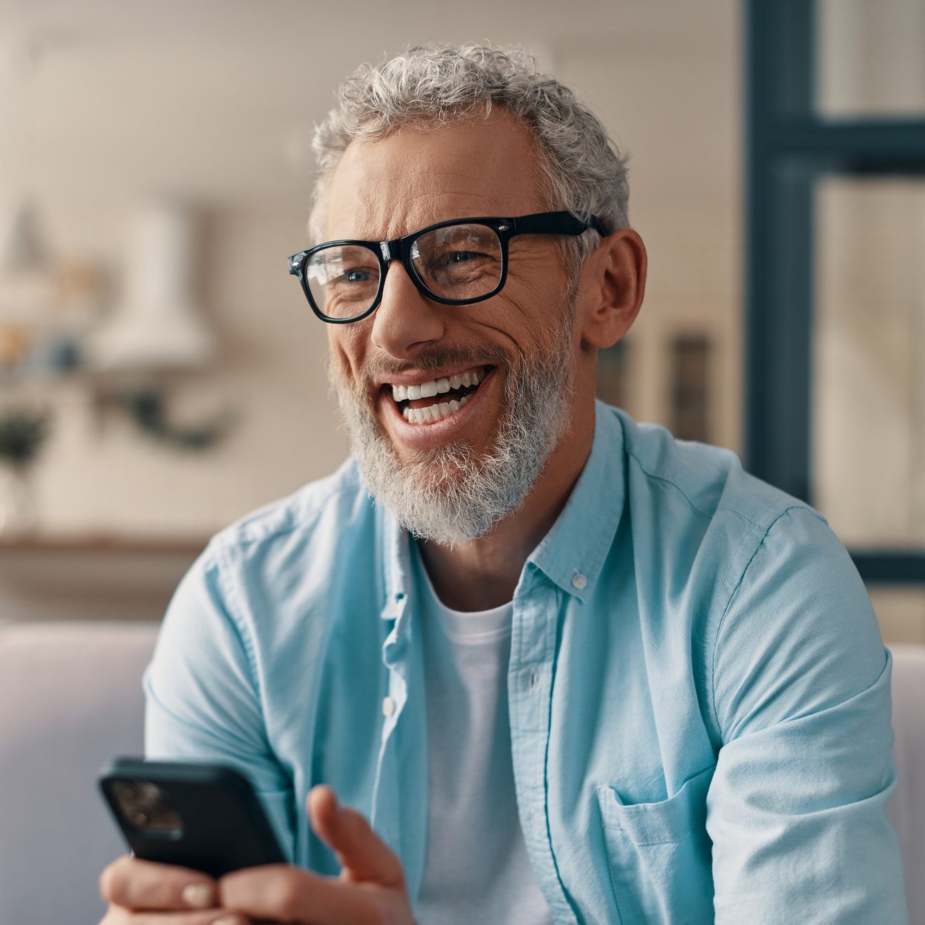 Cheerful senior man phone while sitting on the sofa at home
